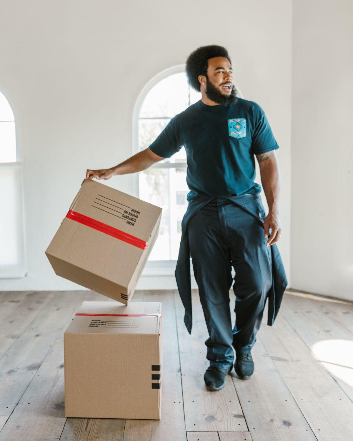 A mover in uniform lifting a sealed box off a stack