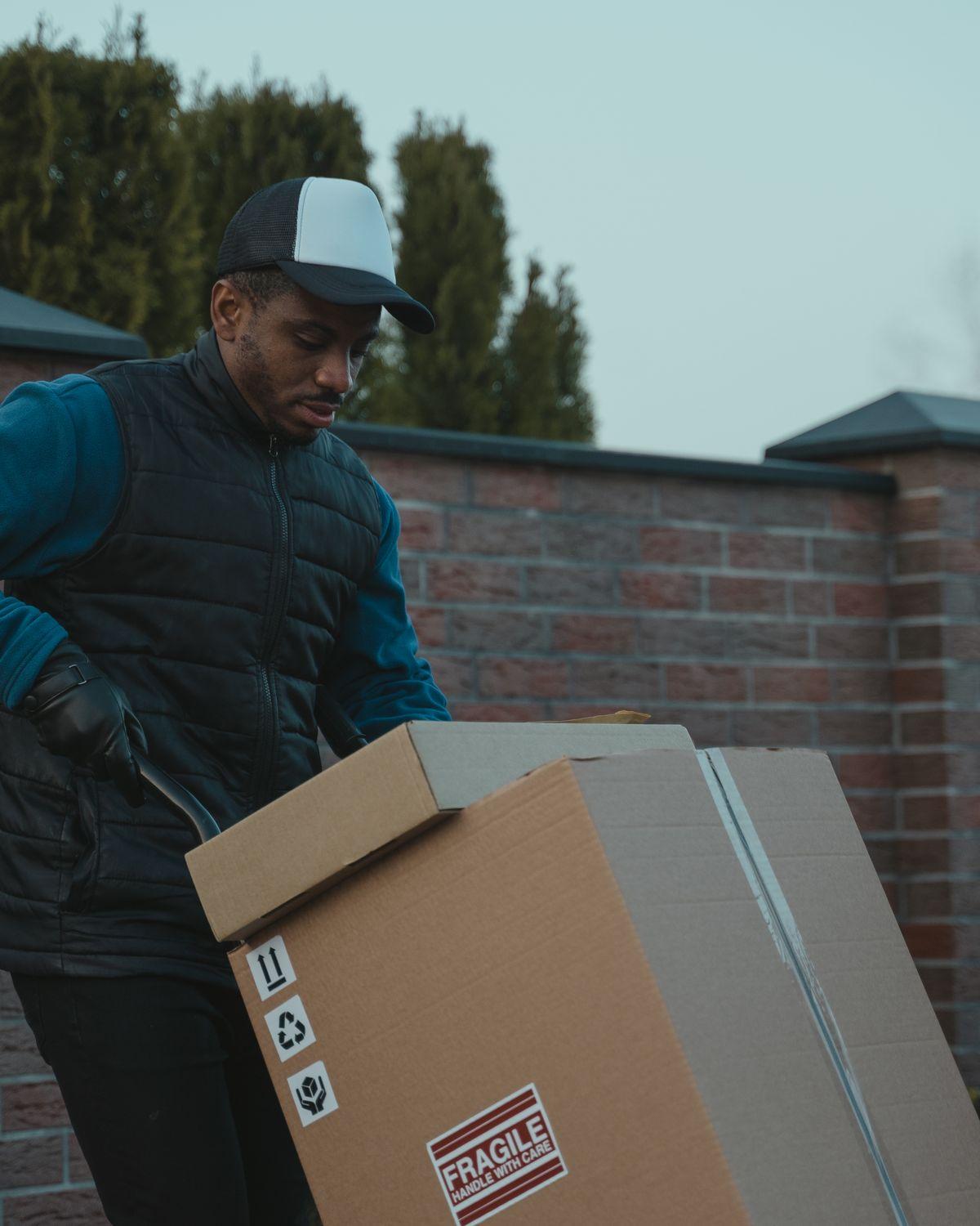 A mover carrying a sealed box towards an open van