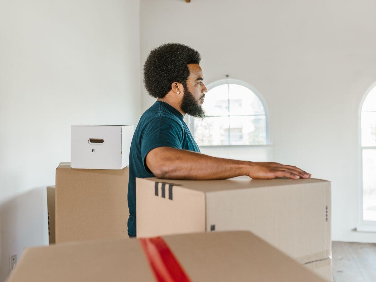 A mover in uniform setting a packed box down in an empty room